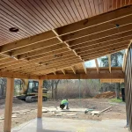 A worker installs wooden ceiling panels in a residential home, showcasing the construction process.