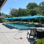 A serene pool scene featuring blue umbrellas and a blue tiled patio, creating a relaxing outdoor atmosphere.