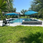 A serene pool scene featuring blue umbrellas and a blue tiled patio, creating a relaxing outdoor atmosphere.