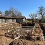 A construction site showing a backyard pool being built, with equipment visible around the site.