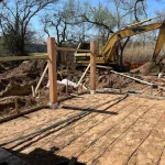 A construction site featuring a digger and a partially built wooden frame structure.