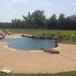 A backyard under construction featuring a pool surrounded by a wooden fence.