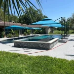 A serene pool scene featuring blue umbrellas and a blue tiled patio, creating a relaxing outdoor atmosphere.