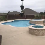 A backyard under construction featuring a pool surrounded by a wooden fence.