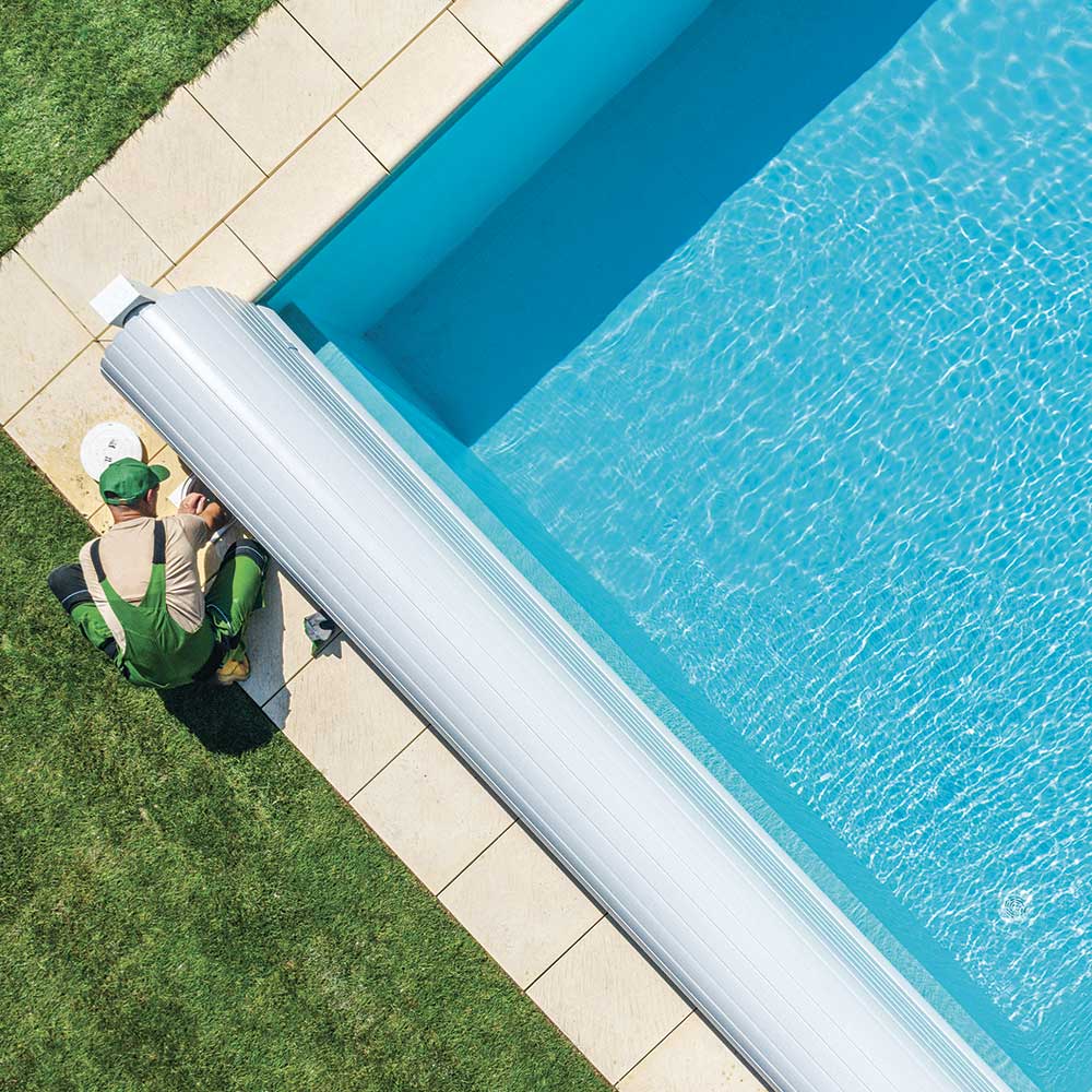 A man sits on the edge of a pool, dipping his feet in the water, enjoying a sunny day.